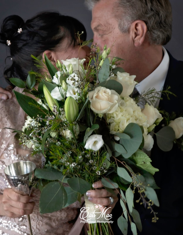 Kissing behind bridal bouquet