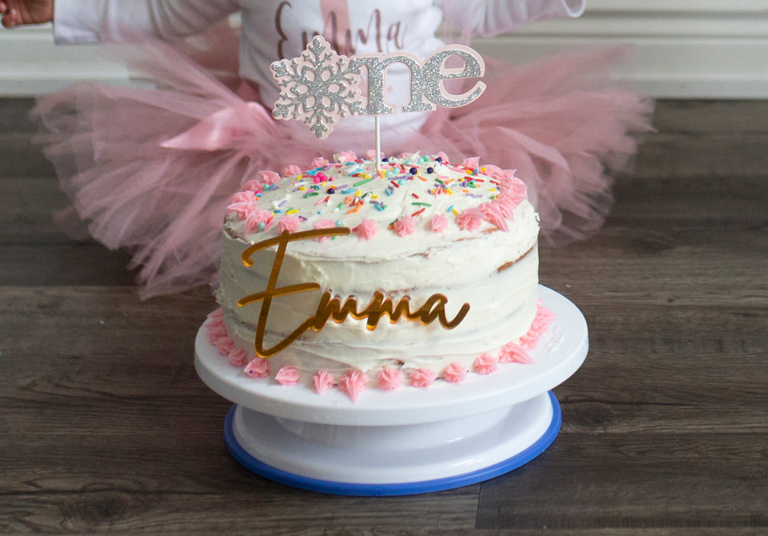 Photo of a one year old birthday cake with baby in pink tutu sitting behind it cake smash photo session