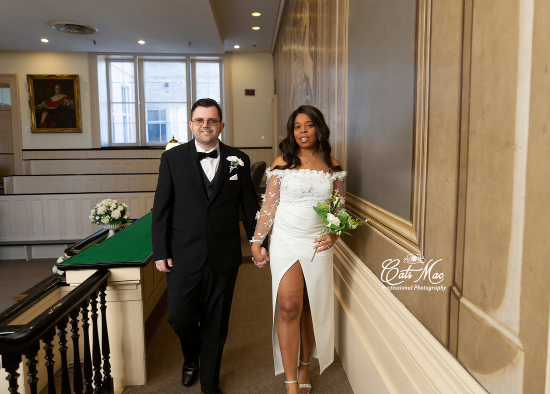 Bride and groom holding bouquet against the natural light from a window Victoria Hall Cobourg