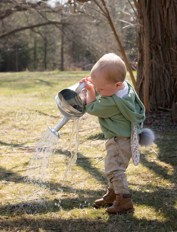 Little boy playing with a silver watering can full of water during a spring photo session