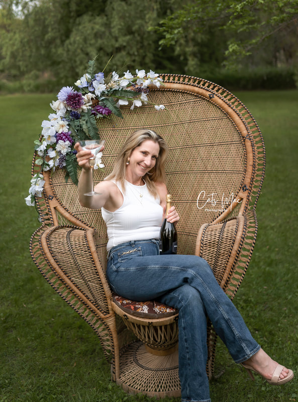 woman sitting on peacock chair holding champagne and bottle for birthday celebration photoshoot