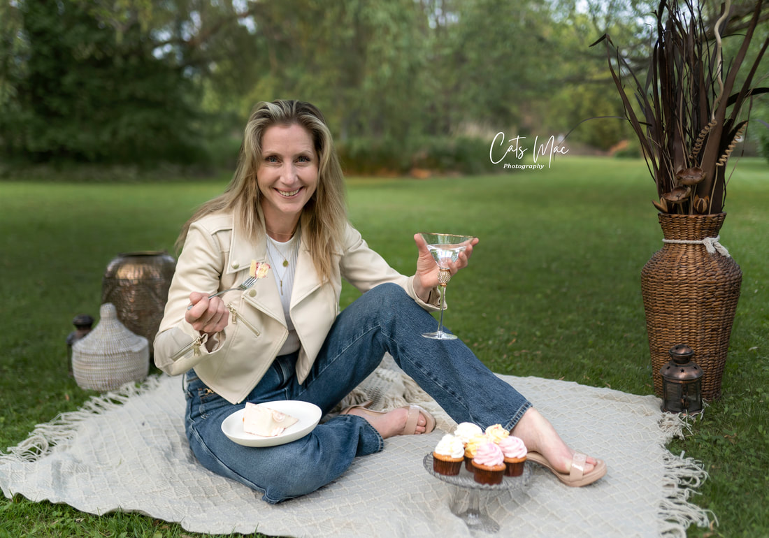 women sitting on blanket on grass eating cake and hold glass of wine adult birthday celebration
