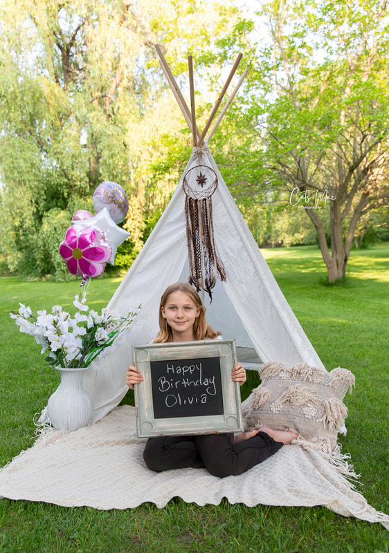 Girl celebrating tenth birthday with a photo shoot teepee behind her balloons