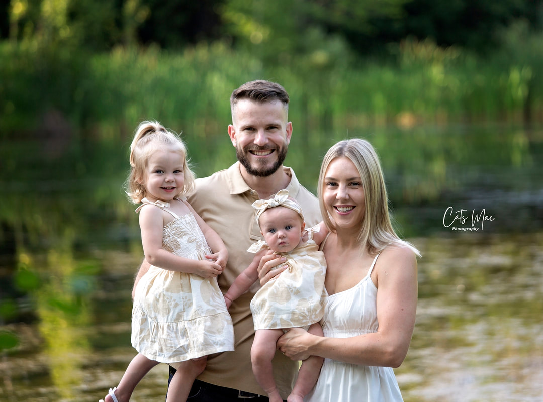 Family Photo Session against a pond. Mom, dad, girl and baby 