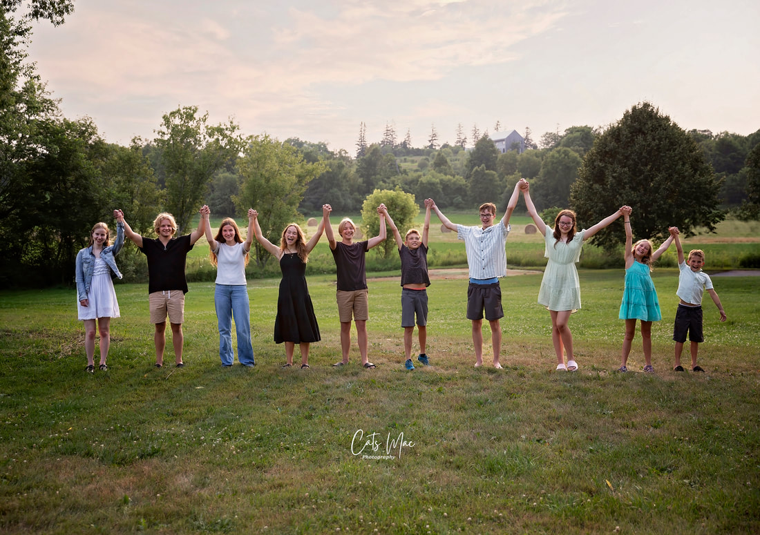 Photo of ten children all cousins holding hands up in field 