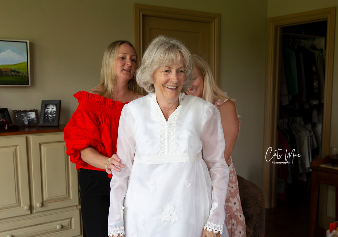 Grown daughters helping their mom into her wedding dress
