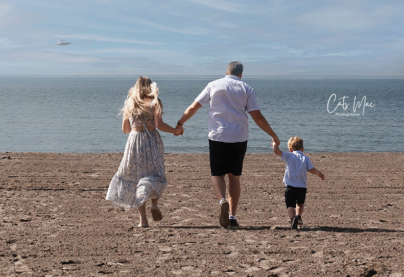 Photo shoot session at Cobourg Beach mom dad and little boy running towards the water 