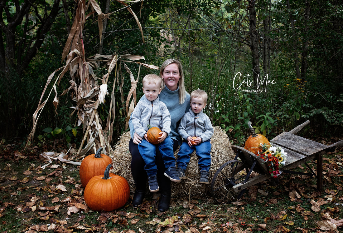 mother and two little boys sitting on bale of straw family fall photo session