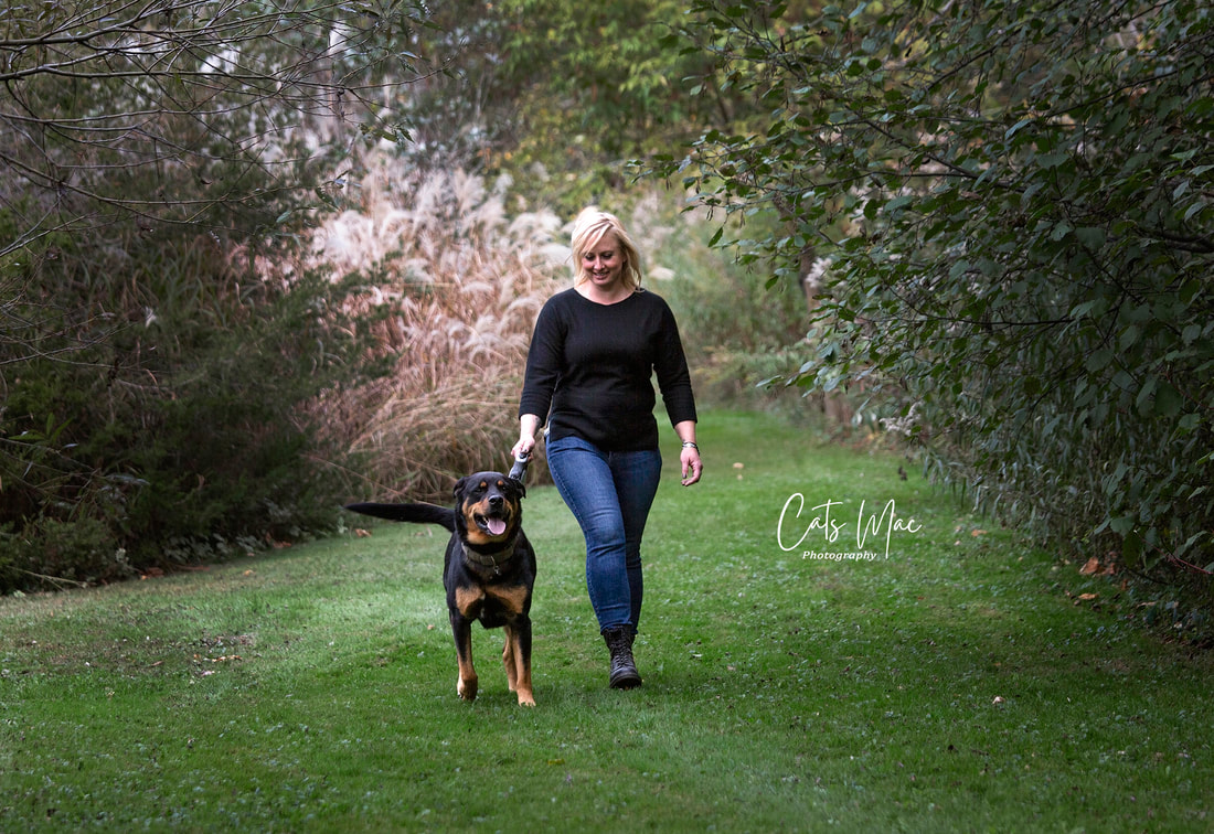womand walking dog on grass with trees around pet family photo session 