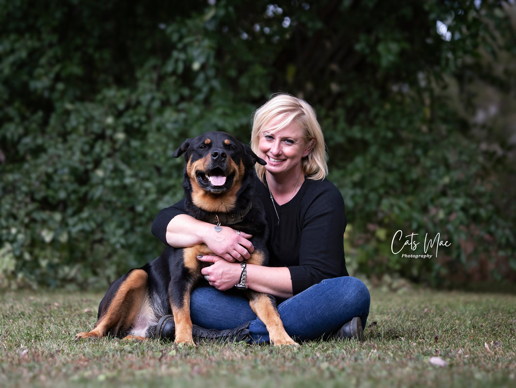 Woman sitting on grass giving her dog a hug. Pet family photo shoot 