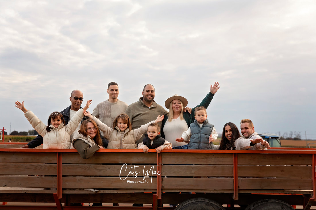 Large family sitting on wagon ride at farm with hands in the air