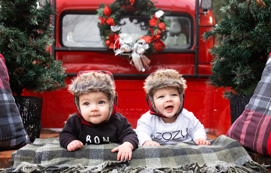 Twin baby boys in back of vintage red truck christmas photo shoot