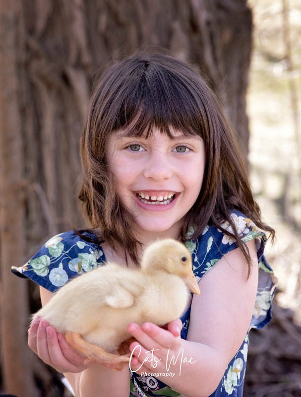Girl hold a baby duck looking at the camera and smiling