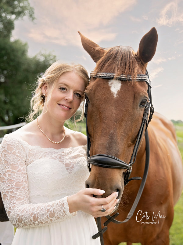 Bride in wedding gown looking at camera while beside her horse