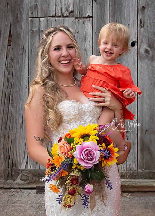 Bride holding little baby in her arms and holding bouquet 
