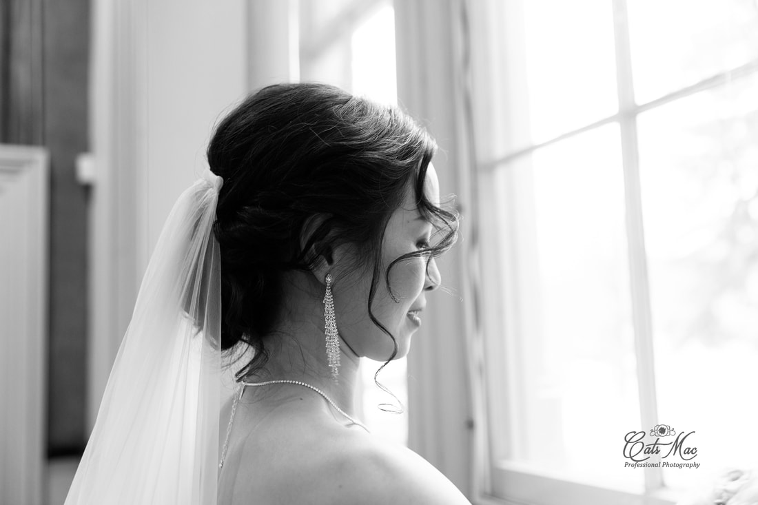 Black and white photo of bride looking out window natural light 