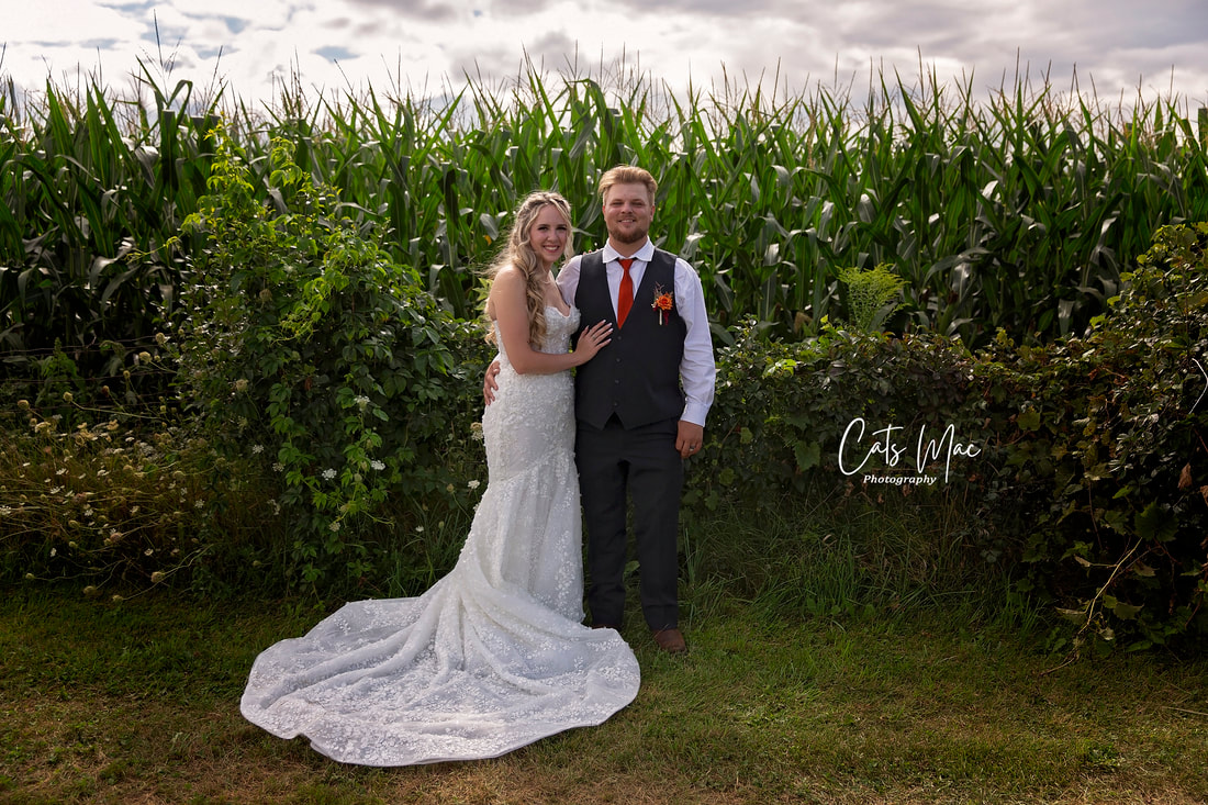 Bride and groom standing outside in front of cornfield wedding