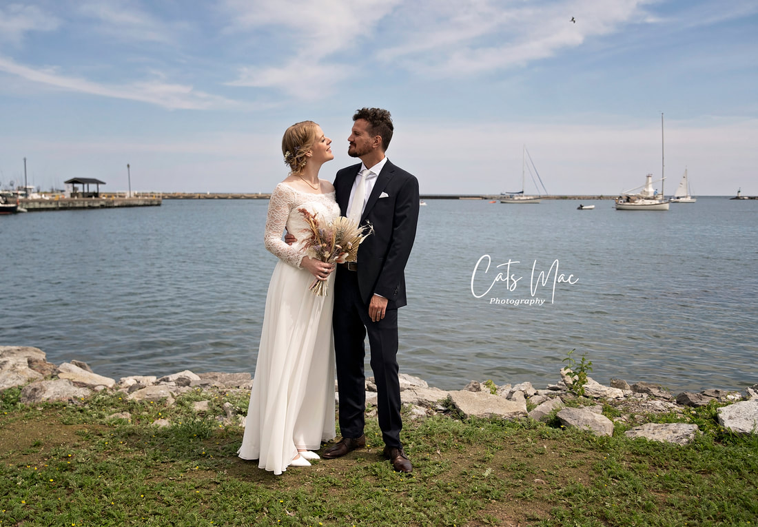 Bride and groom looking at each other at Cobourg Marina and Yacht club with water and sailboats in the background