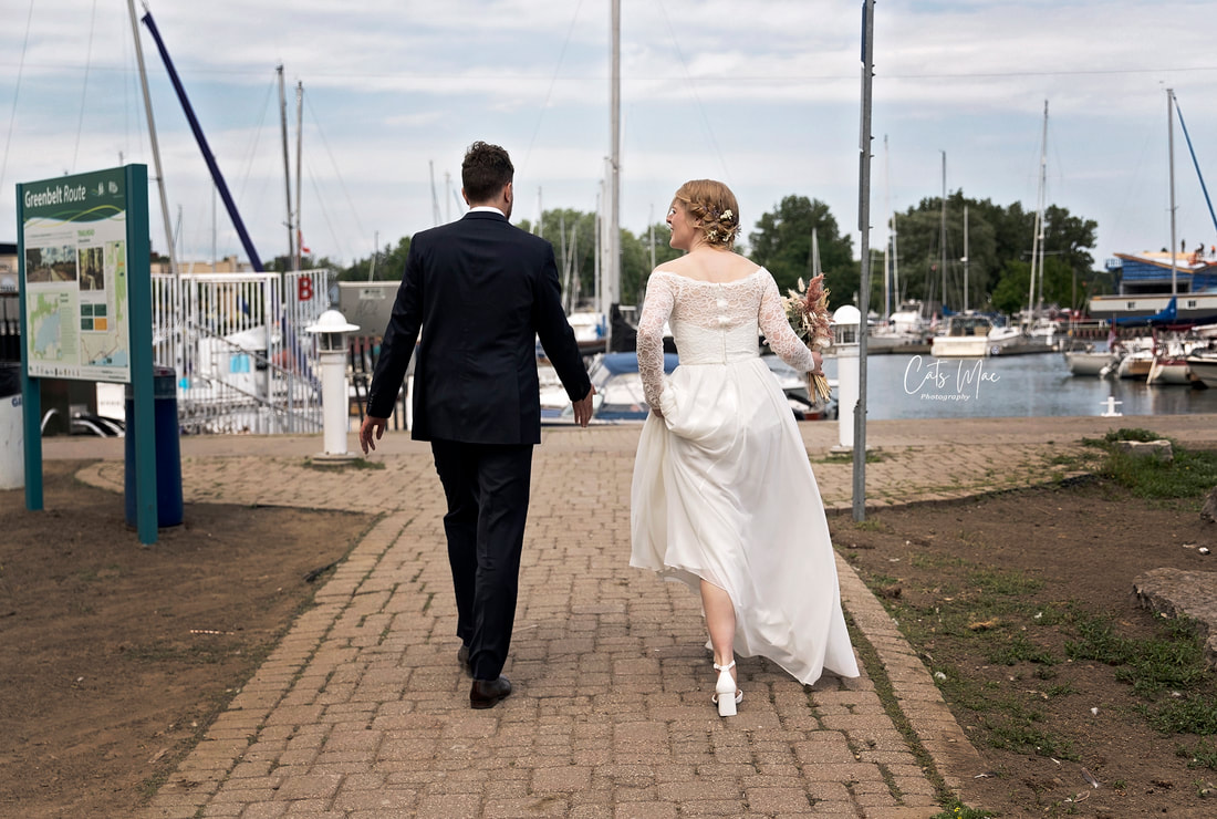 Photo of the back of a bride and groom walking towards their yacht at Cobourg Marina Ontario