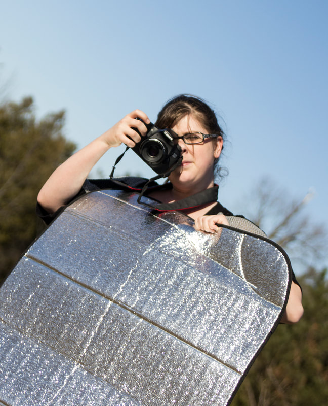 Jenn Schofield photographer with camera and reflector