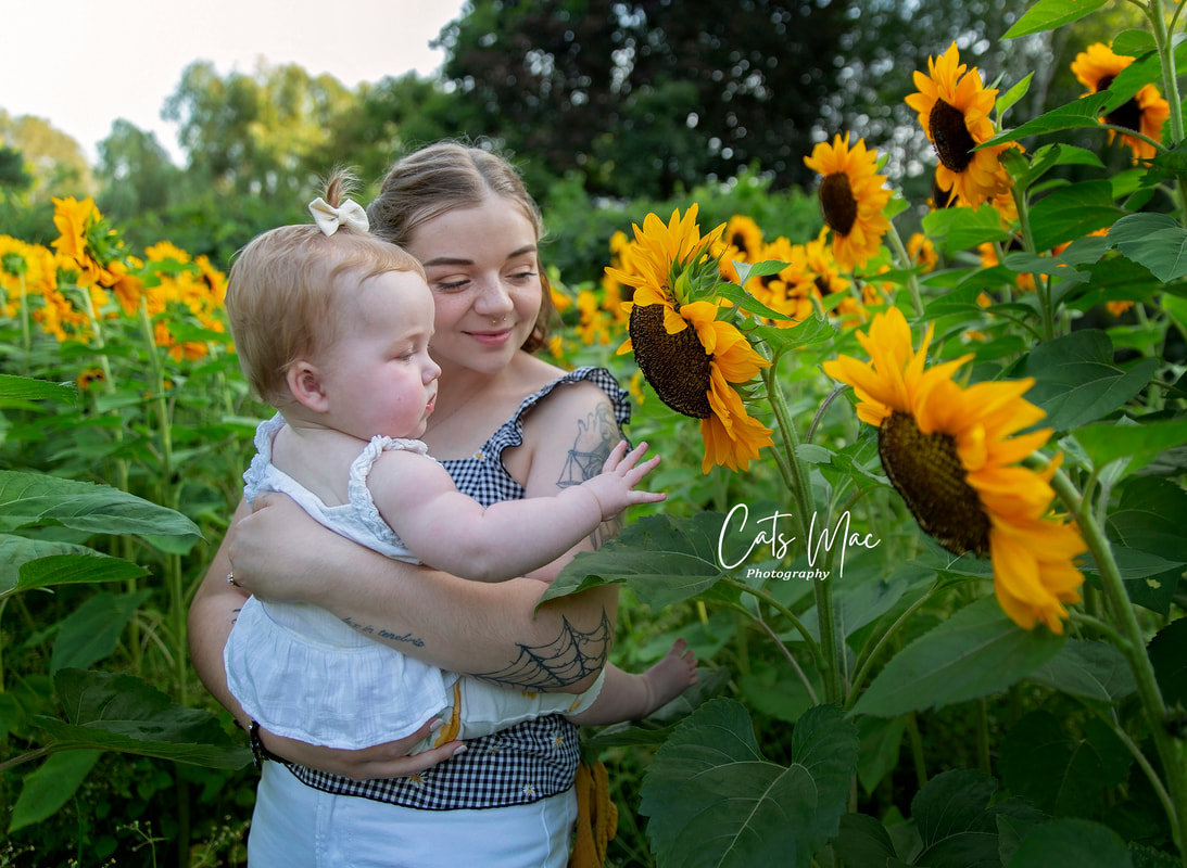 Mom holding a baby in a sunflower patch